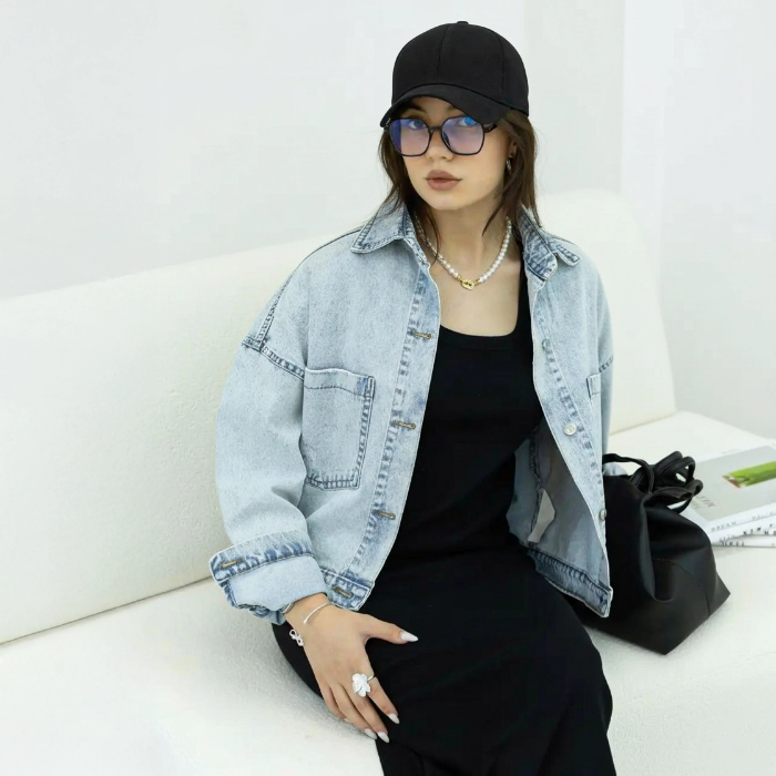 کت جین زنانه نیم‌تنه (کراپ) زاپ‌دار اسکای جین رنگ آبی روشن، با جزئیات پارگی‌های مد روز روی پارچه.